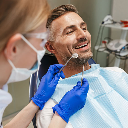 middle-aged-man-in-dentists-chair young girl with invisible braces